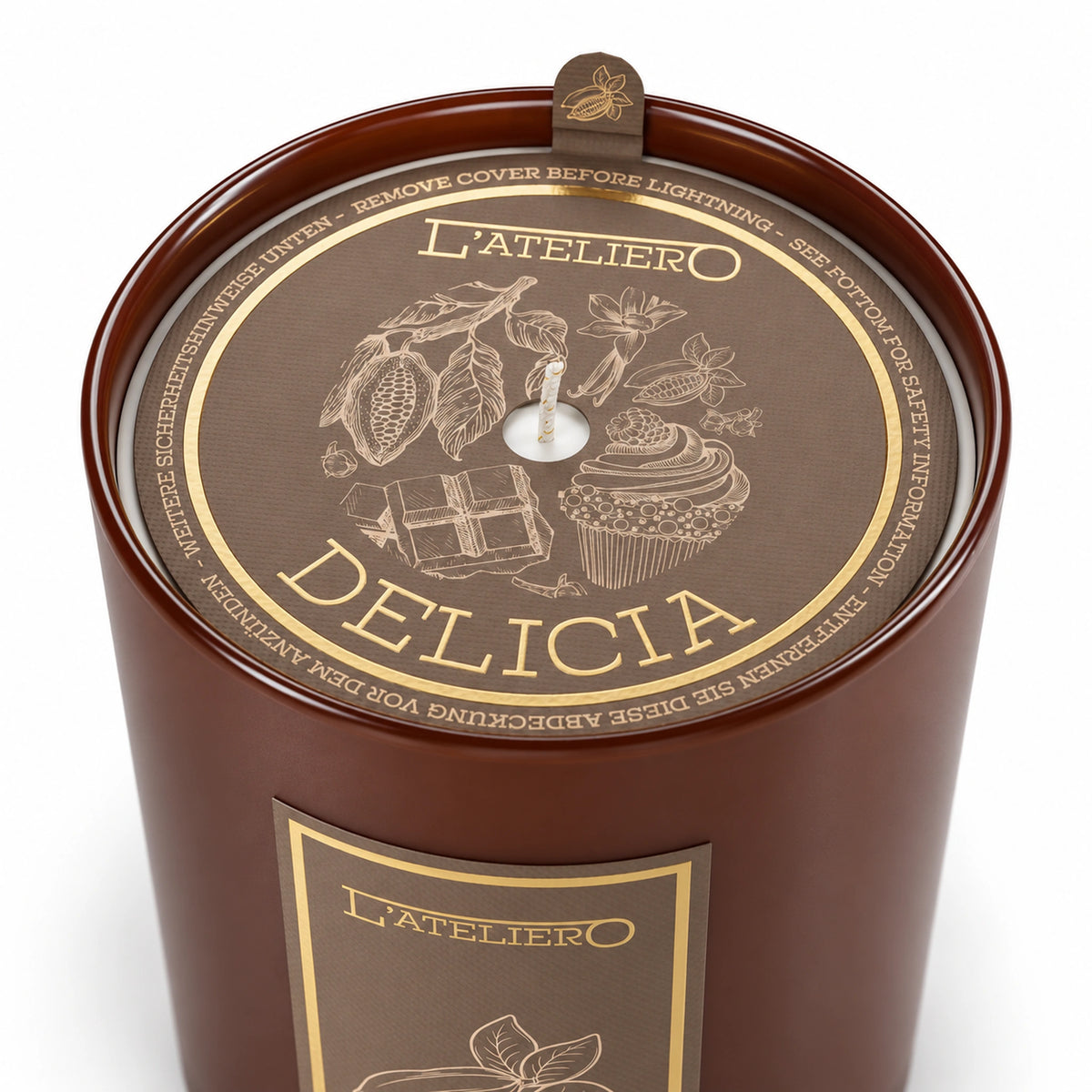 L’ATELIERO Delicia Duftkerze schräg von oben: braunes Glas und Schutzabdeckung mit goldenen Kakao-, Schokoladen- und Gebäckmotiven.